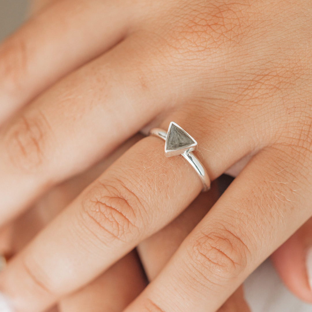 This close up photo shows the Triangle Cremated Remains Stacking Ring in Sterling Silver, designed by close by me jewelry, on a model's ring finger