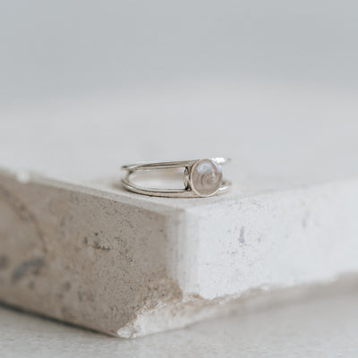 Pictured here is the Twin Band Ring designed by close by me jewelry and then set with ashes in Sterling Silver lying flat on a stone