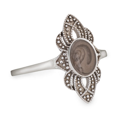Pictured here is a close-up side view of Close By Me Jewelry's vintage-style WWII Cremation Ring in Sterling Silver, featuring a large oval bezel containing solidified ashes.